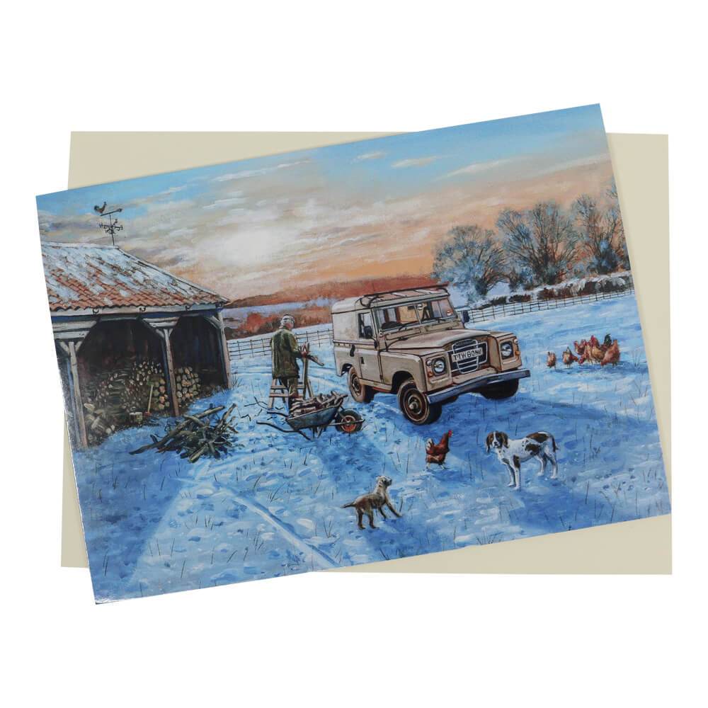 This wonderful traditional style Land Rover Christmas card features a Land Rover Series 3 set in a snow-covered field next to the woodpile with the farmer sawing firewood.